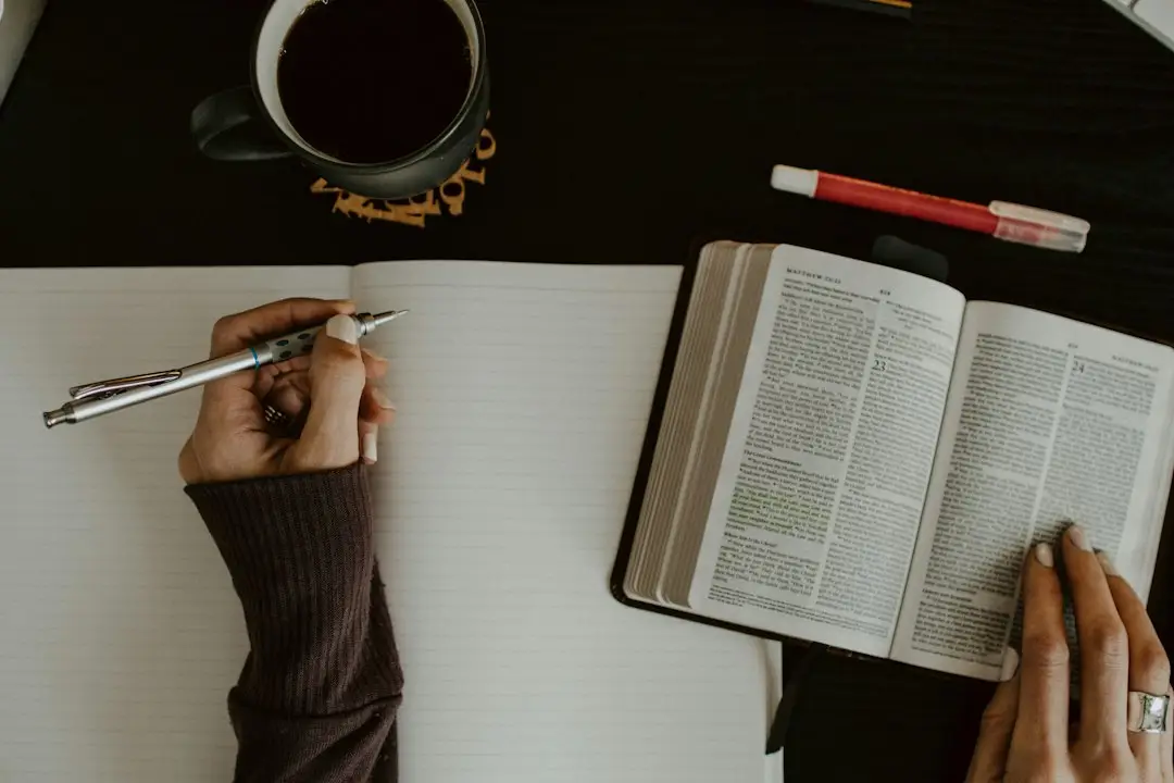 Open Bible and notebook on a table as someone studies Scripture and writes notes